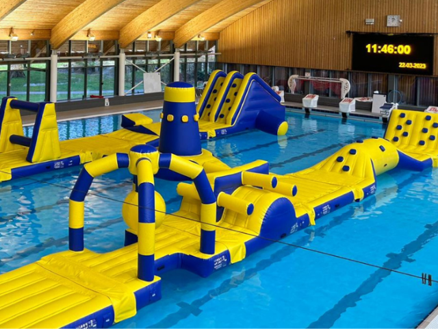 Large blue and yellow inflatable taking up the full length of a swimming pool.