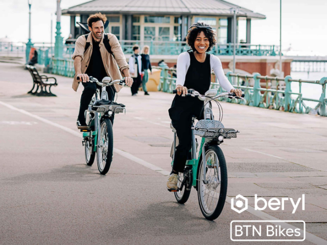 Two people riding bikes along a seafront
