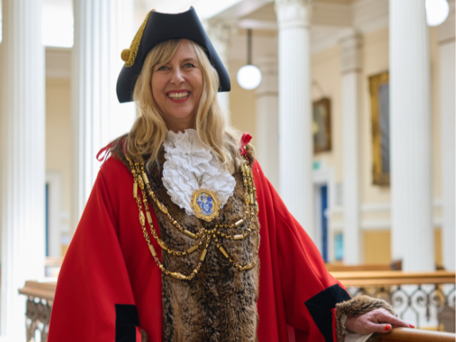 Councillor Theresa Fowler dressed in mayoral robes standing in front of white pillars 