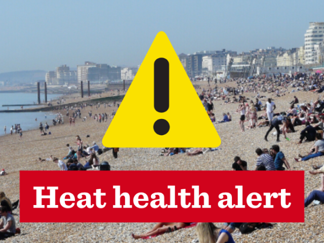 Brighton beach with yellow warning sign in the centre. Text reads: "Heat health alert"