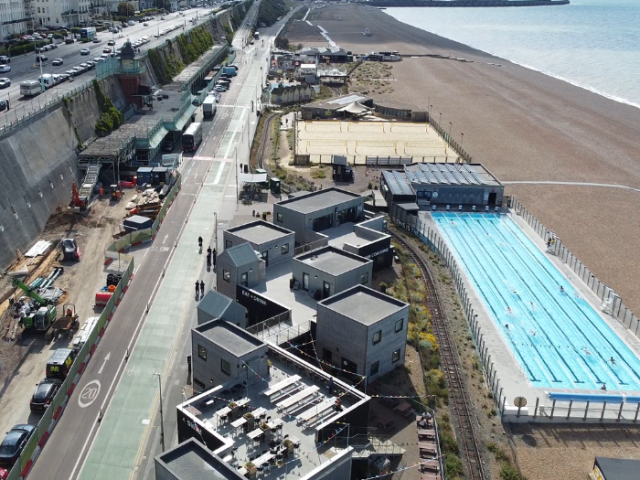 A picture of a seafront with a swimming pool and road