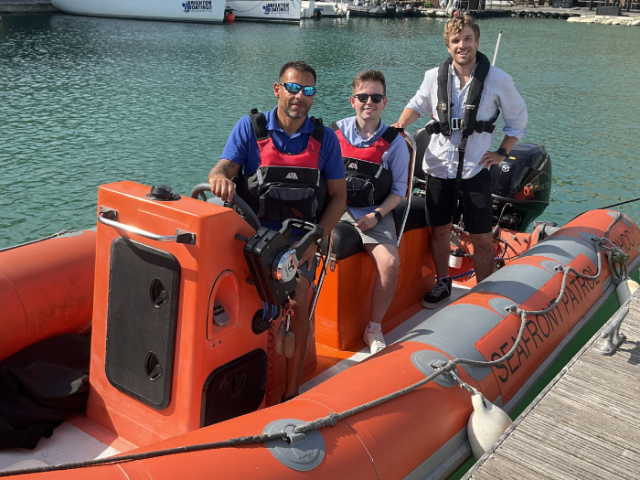 Three men in lifejackets on an orange boat.