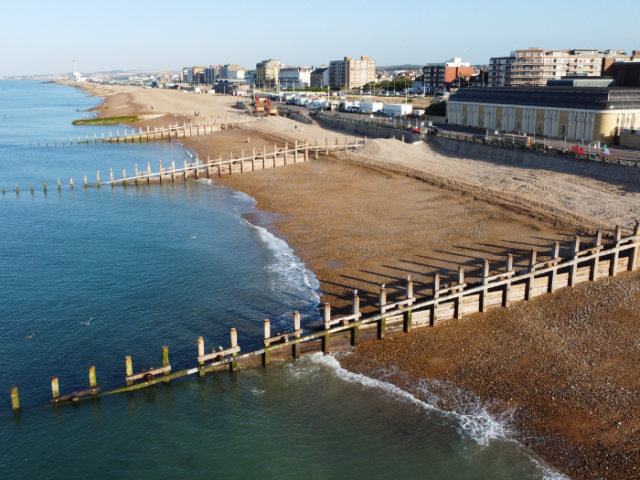 A picture of a pebble beach, the sea and timber groynes