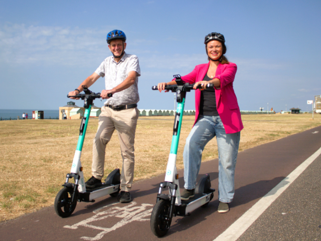 two people posing on e-scooters