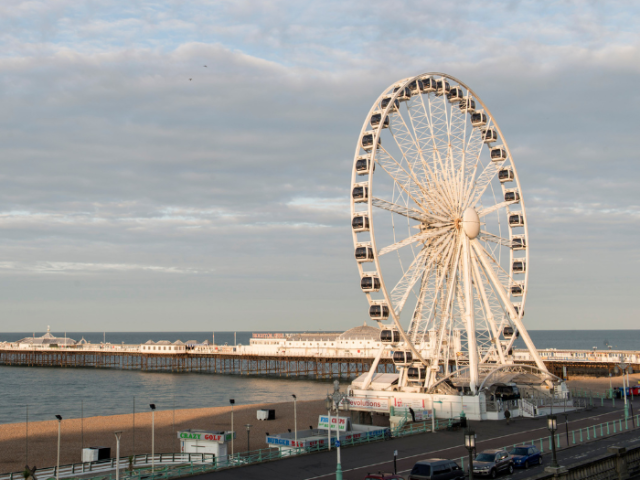 A large white wheel on the beach in Brighton.