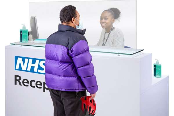 Person speaking to receptionist at an NHS clinic.