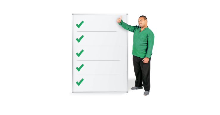 Person standing by a large board with a list and check marks on it.