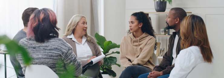 group of people sitting on chairs in a circle as part of a support group