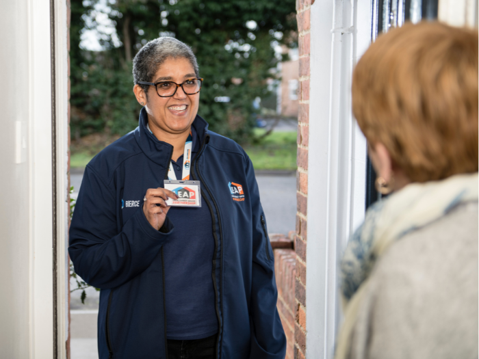 A landlord is standing at an open front door showing their ID to a tenent.