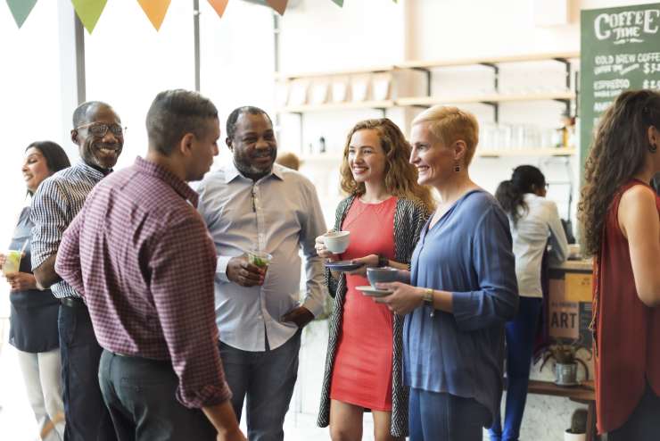 A group of people standing in a circle in a coffee shop having a conversation