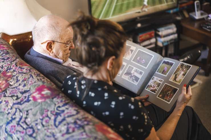 An image looking over the shoulders of 2 people looking at a photograph album