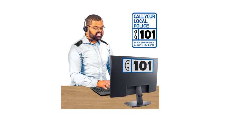 Man in police uniform sat at a desk at a computer, with a phone headset on. Text saying to call 101.