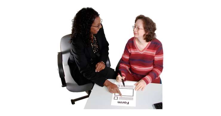 Woman giving another woman help with filling out a form
