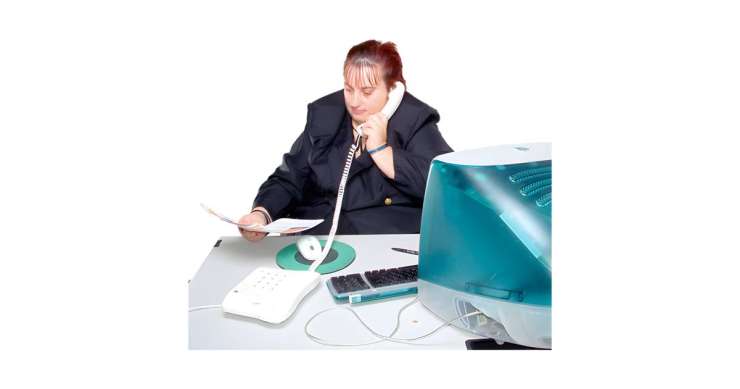 Person sat an office desk speaking on the phone.
