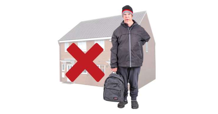 Person with a rucksack in front of a house which has a red cross on it.