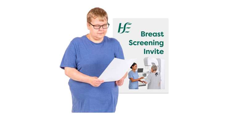 A person in a blue shirt looks at a piece of paper. Beside them is a poster about breast screening, showing a nurse helping a patient with a mammogram machine.
