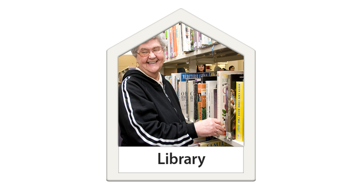 Person standing in front of a row of books in a library setting.