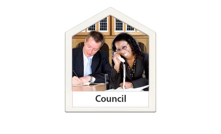 Two council workers sitting at a desk. One is on the phone and one is writing. 