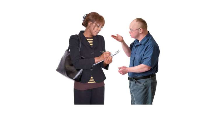 A woman taking notes while a man gestures during a conversation.