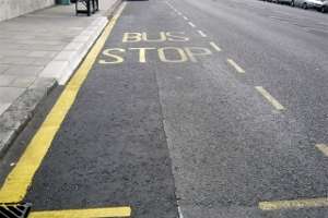 Photograph showing bus stop markings on a road, the markings are in bright yellow